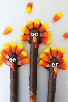 three candy sticks decorated like turkeys with candy cornucions on them and eyes