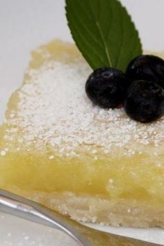 a close up of a slice of pie on a plate with blueberries and powdered sugar