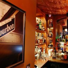 a bar with liquor bottles on the shelves and an advertisement for bourbon in front of it