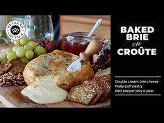 a wooden cutting board topped with different types of breads and grapes next to a glass of wine