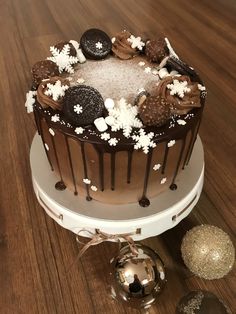 a chocolate cake with white frosting and sprinkles sits on a table