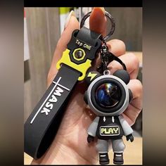 a person holding a camera keychain with an object in it's hand