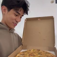 a man looking at a pizza in a box