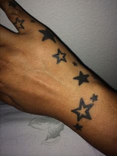 a person's hand with stars tattooed on the left side of their arm and wrist