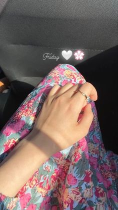 a woman is holding her hand out in the back seat of a car while wearing a floral dress