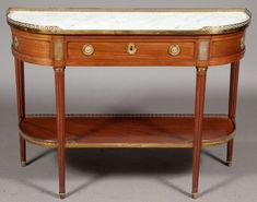 an antique console table with marble top and gold trimmings on the bottom shelf