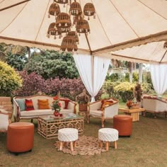 an outdoor living area with couches, chairs and tables under a large white tent