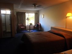 a bed room with a neatly made bed next to a chair and a table in front of a sliding glass door