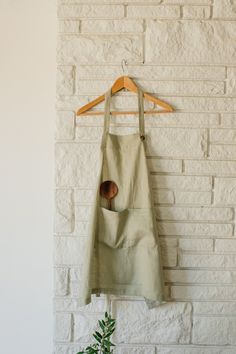 an apron hanging on a brick wall with a potted plant in the foreground