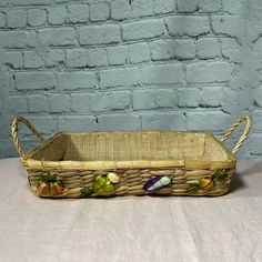 a wicker fruit basket with handles on a white tablecloth against a blue brick wall