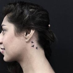 a woman's neck with small birds on her left side behind the right ear