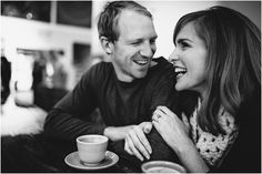 a man and woman sitting next to each other at a table with coffee in front of them