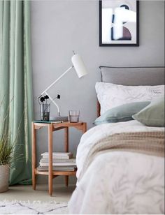 a bed room with a neatly made bed and a night stand next to a window