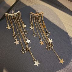 Shoot for the stars, or at least be seen from the stars in these shiny Gold Star Tassel Statement Earrings! Make a sweeping statement at your next formal event! DETAILS & SIZE Finish: Gold plate Material: Alloy; CZ stones; .925 sterling silver ear wire Measurements: Length: approx. 3" Comes with friction earring backs Shop the Celestial collection for more options! Or shop Earrings for more options! Elegant Star Charm Earrings For Party, Elegant Party Earrings With Star Charm, Shoot For The Stars, Fairy Charms, Gold Statement Earrings, Tassel Jewelry, Shooting Stars, Gold Star, Earrings Photo