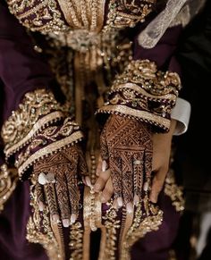 the hands and arms of a woman wearing henna designs on her hands, with gold detailing