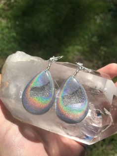 These holographic Teardrop geode earrings made from resin shift from clear to a beautiful sparkly rainbow. They are lightweight and won't bother your ears. Made by Katie Glover Resin Art by Katie 2020 Contact me on my Instagram @123pour if you would like additional photos or videos of this product.Please be aware that this is handmade art and perfection has no place in art. However, this was crafted with love and intention and I hope you are satisfied with your purchase. Your purchase is not ref Silver Resin Drop Earrings, Hypoallergenic Rainbow Drop Earrings, Iridescent Teardrop Hypoallergenic Jewelry, Unique Iridescent Teardrop Earrings, Nickel-free Silver Resin Earrings, Iridescent Resin Drop Earrings, Iridescent Dangle Resin Earrings, Iridescent Sparkling Dangle Earrings, Sparkling Iridescent Dangle Earrings