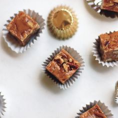 several pieces of dessert sitting on top of each other next to foil wrappers and cupcakes