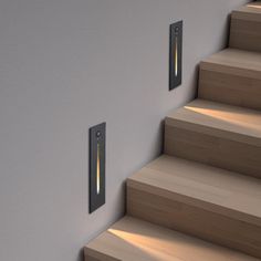 two lights are on the wall next to some stairs and wood steps with light coming from them