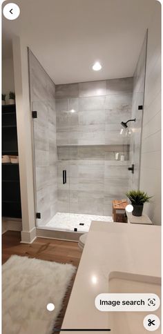 a bathroom with a walk in shower and white rugs on the floor next to it