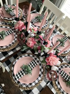 the table is set with pink plates and plaid placemats, black and white checkered napkins