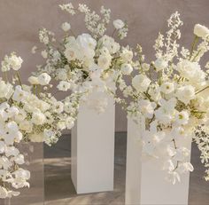 three vases filled with white flowers on top of a table