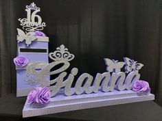 a purple and silver cake with the word grand written on it, surrounded by flowers