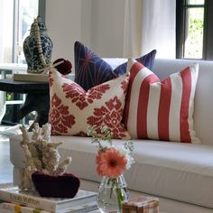 a living room filled with lots of furniture and pillows on top of white couches