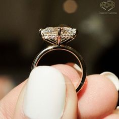 a close up of a person's hand holding a ring with a diamond on it