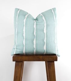 a blue and white pillow sitting on top of a wooden stool