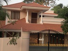 a house that is in the middle of a fenced area with an iron gate