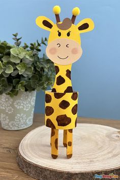 a cardboard giraffe standing on top of a wooden table next to a potted plant