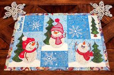 a quilted placemat with snowmen and christmas trees on the front, along with an ornament