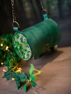 This beautiful bag is made in resin and leather. Is inspired in a koi pond, it has a different fishes and plants. They are handmade so can be different. Perfect for a goblincore or druid look, to wear as a shoulder bag. Very confortable. Size: 21cm and 11cm diameter Handmade in Leather and Epoxi Resin. Green Bucket Shoulder Bag Gift, Green Bucket Shoulder Bag For Gift, Unique Green Bag As A Gift, Unique Green Bag For Gift, Green Hand-painted Bag As Gift, Hand Painted Green Rectangular Shoulder Bag, Green Hand Painted Rectangular Shoulder Bag, Green Hand Painted Bags For Gift, Handmade Unique Green Bags