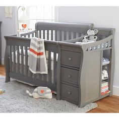 a baby crib with two drawers and a stuffed animal on the floor next to it