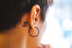 a person with a tattoo on their ear and behind the ear is an omen symbol