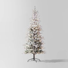 a white christmas tree with snow on the branches and lights in front of a gray background