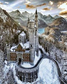 an aerial view of a castle in the middle of mountains with snow on the ground