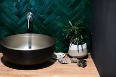 a black bowl sitting on top of a wooden table next to a potted plant