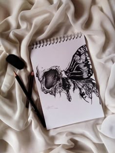 a spiral notebook with a drawing of a butterfly on it