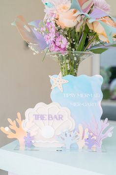 a vase filled with flowers sitting on top of a table next to a sign that says the bar