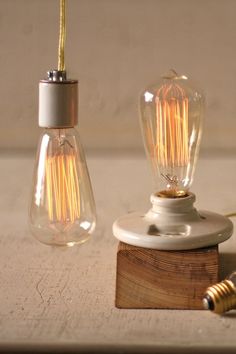 two light bulbs sitting on top of a wooden block next to a small lamp bulb