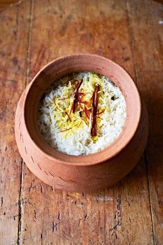 a bowl filled with rice and sauce on top of a wooden table