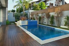 an empty swimming pool with wooden decking next to a fenced in backyard area