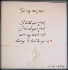 a white card with a silver heart on it that says to my daughter i held you first, i loved you first, and my heart will always be tied to yours