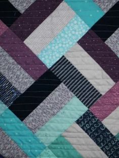 a close up of a quilt with many different colored strips on the top and bottom