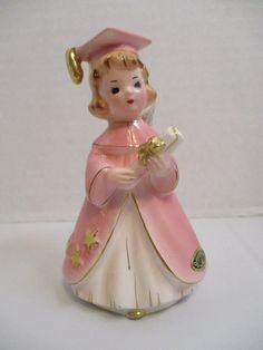 a pink and white figurine holding a piece of paper in its hand on a white surface