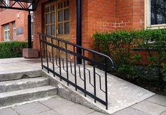 an iron hand rail on the steps leading to a brick building