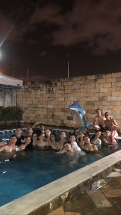 a group of people sitting in a swimming pool at night