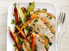 a white plate topped with chicken, carrots and broccoli covered in sauce