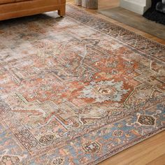 an orange and blue area rug on the floor in front of a brown leather couch